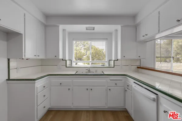a kitchen with white cabinets and a window