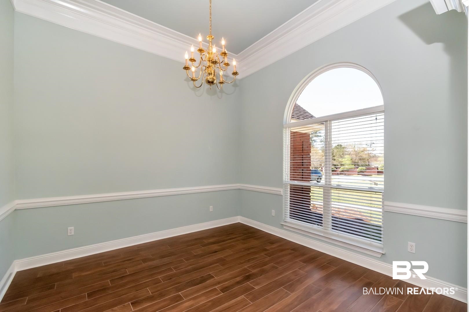 6090 Celeste Road Saraland, AL 36571 - Photo 4 of 38 Spare room with dark wood-style floors, crown molding, baseboards, and a chandelier