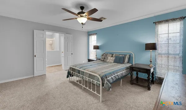 a spacious bedroom with a bed a chandelier and a desk