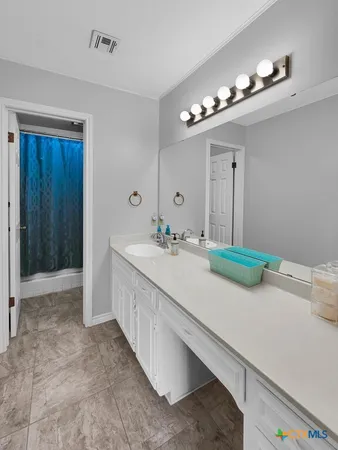 a bathroom with a sink a large mirror and a light fixture