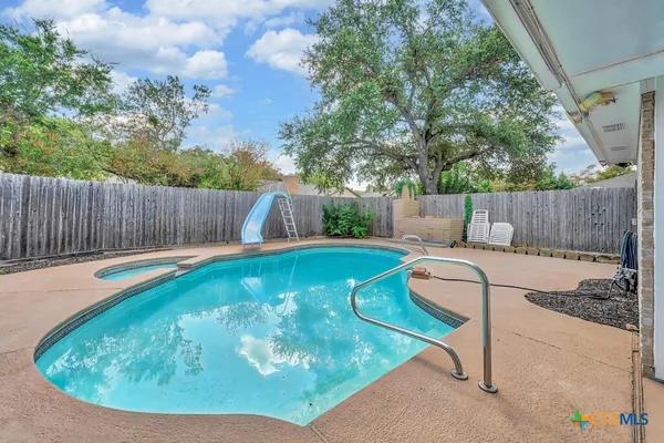 a view of a swimming pool with a couches chairs and a yard