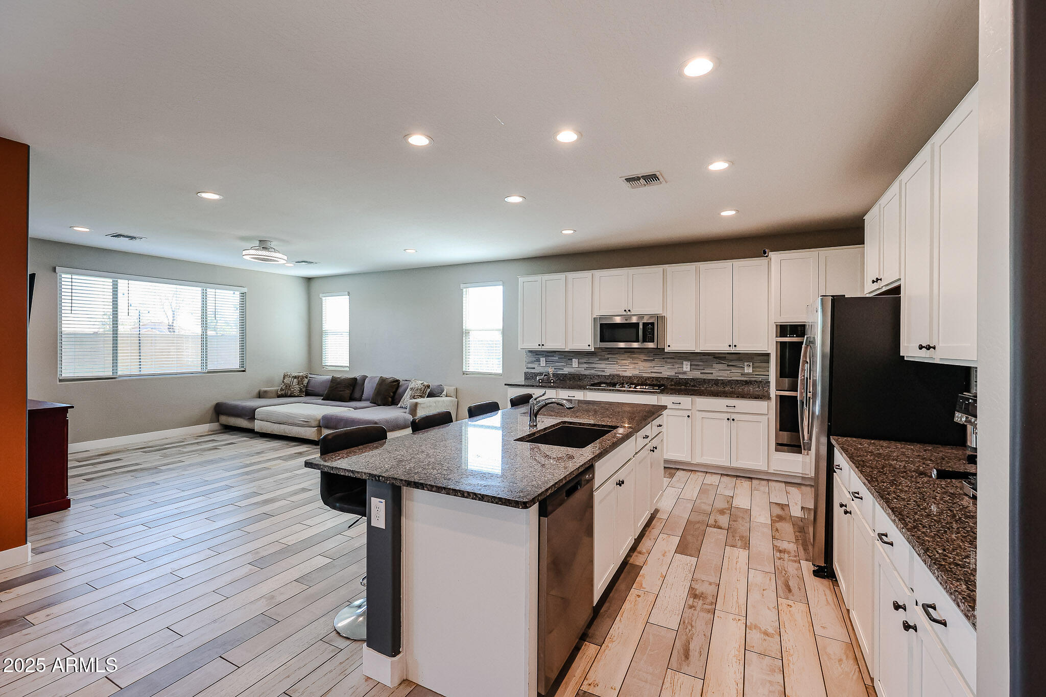 3907 South 75th Drive Phoenix, AZ 85043 - Photo 25 of 49 a kitchen with stainless steel appliances granite countertop a stove top oven a sink dishwasher a refrigerator and white cabinets with wooden floor