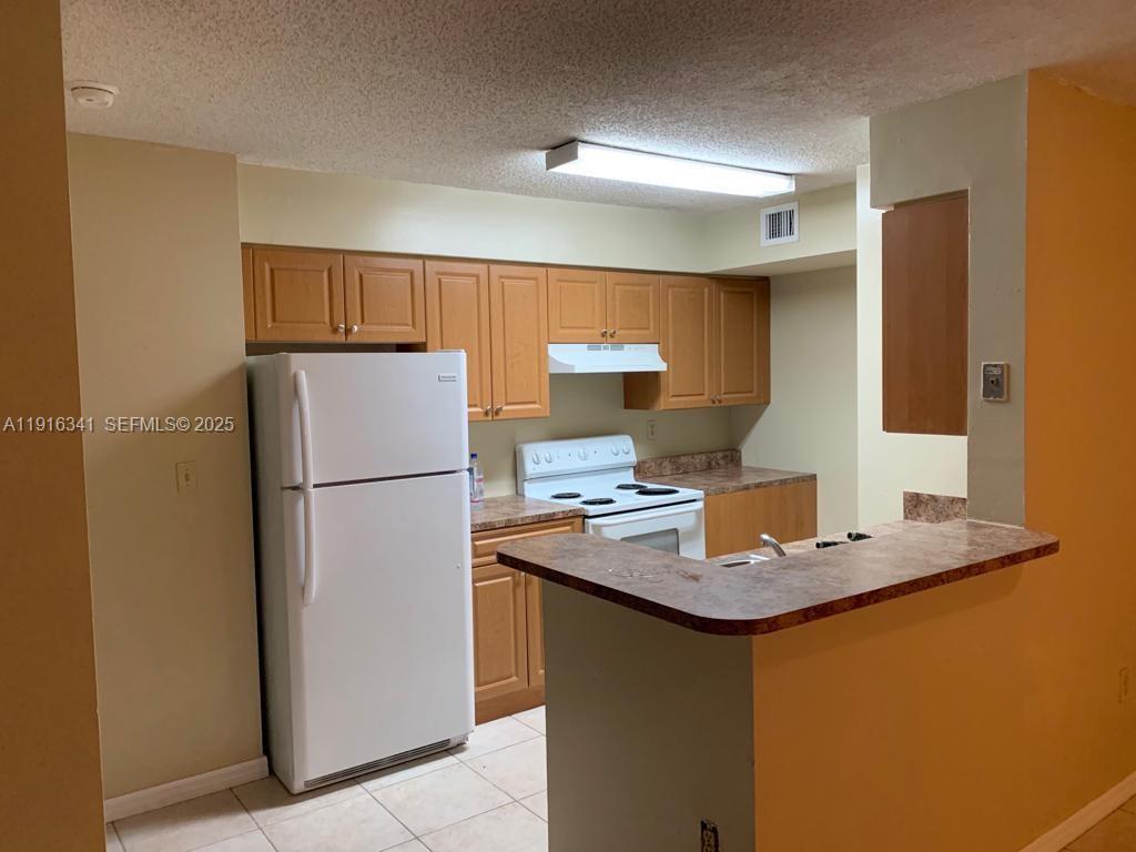 15221 Southwest 80th Street, Unit 404 Miami, FL 33193 - Photo 2 of 6 a kitchen with refrigerator sink and stove