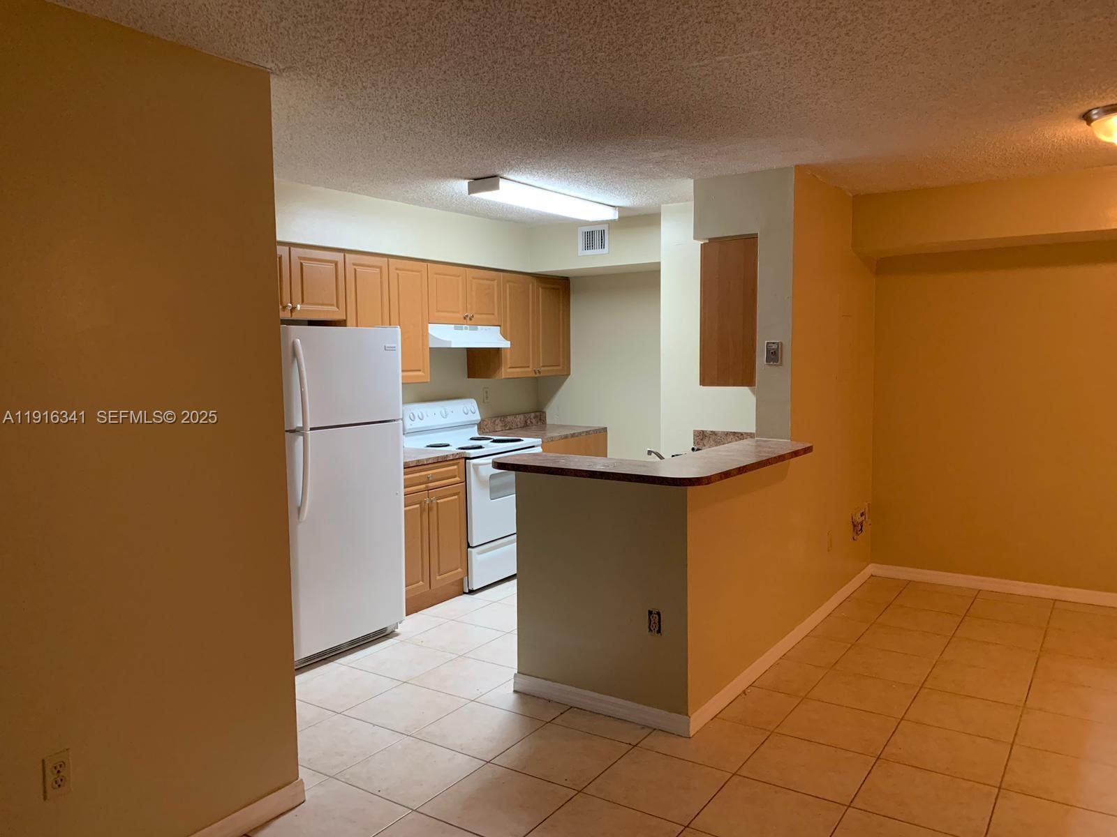 15221 Southwest 80th Street, Unit 404 Miami, FL 33193 - Photo 6 of 6 a kitchen with stainless steel appliances granite countertop a refrigerator a stove and a sink