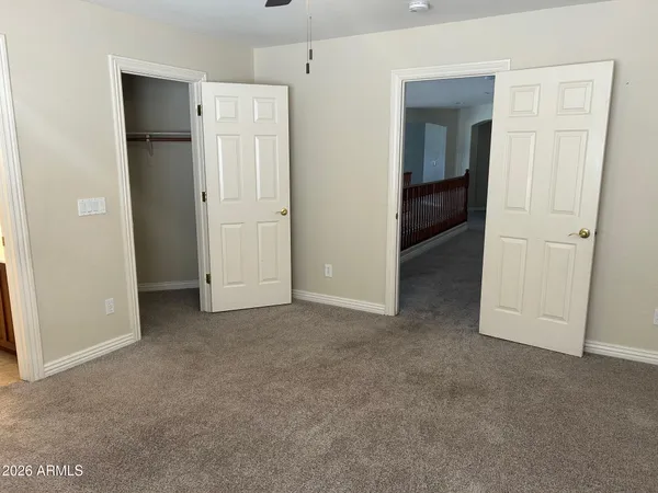 an empty room with windows and chandelier fan