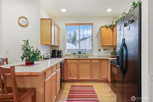 a kitchen with stainless steel appliances a sink a refrigerator a counter space and a window