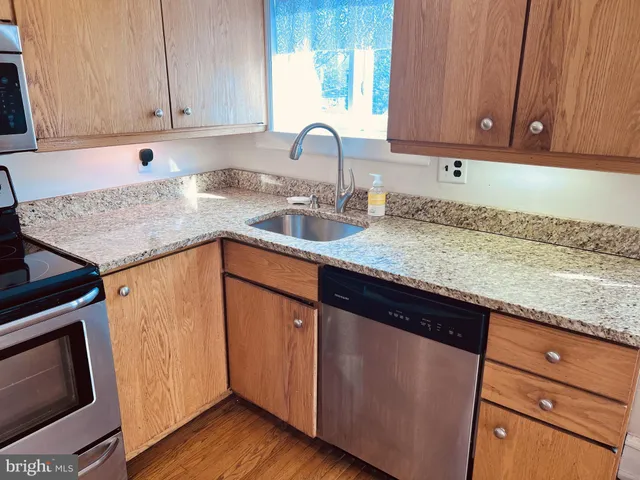 a kitchen with granite countertop wooden cabinets a sink and dishwasher
