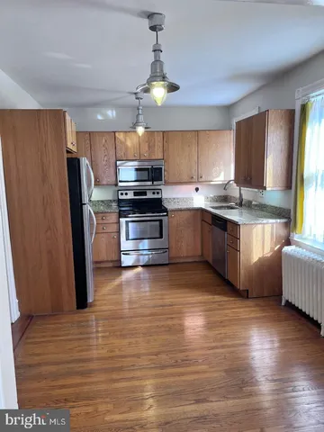 a kitchen with stainless steel appliances granite countertop a refrigerator a stove a sink dishwasher and white cabinets with wooden floor