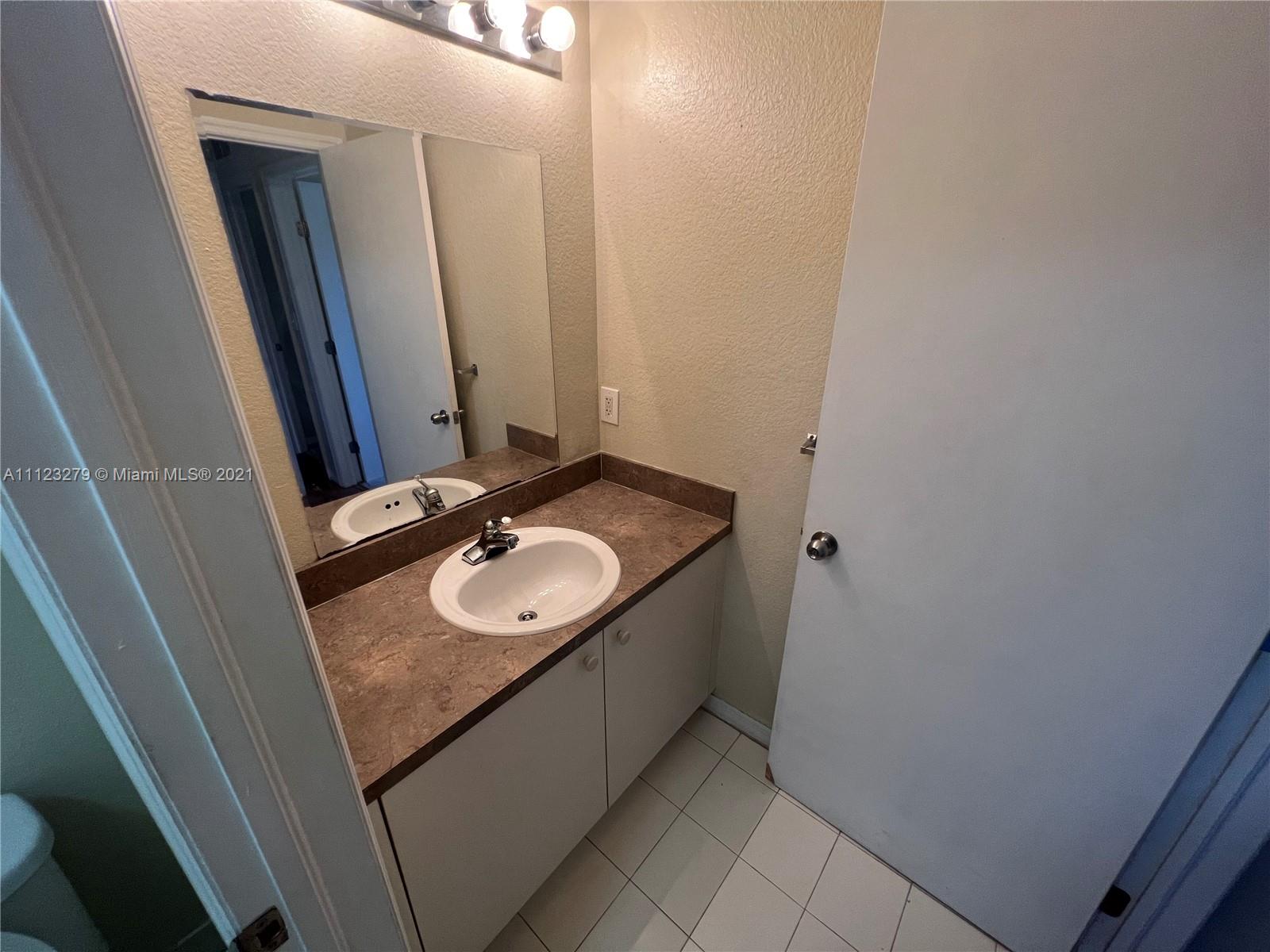 20441 Northwest 15th Avenue, Unit 8 Miami Gardens, FL 33169 - Photo 15 of 30 a bathroom with a granite countertop sink and a mirror