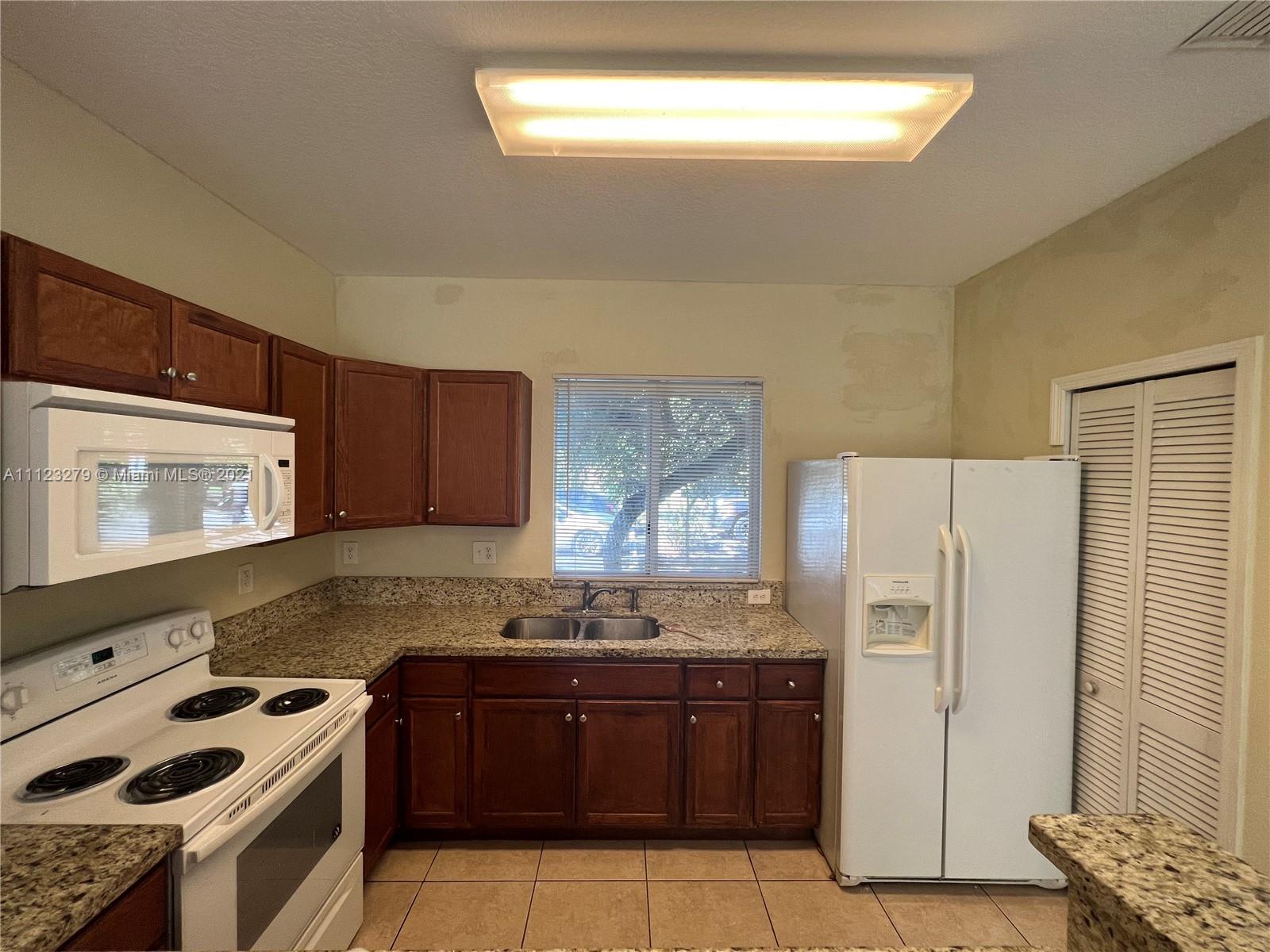 20441 Northwest 15th Avenue, Unit 8 Miami Gardens, FL 33169 - Photo 8 of 30 a kitchen with granite countertop a refrigerator stove and microwave