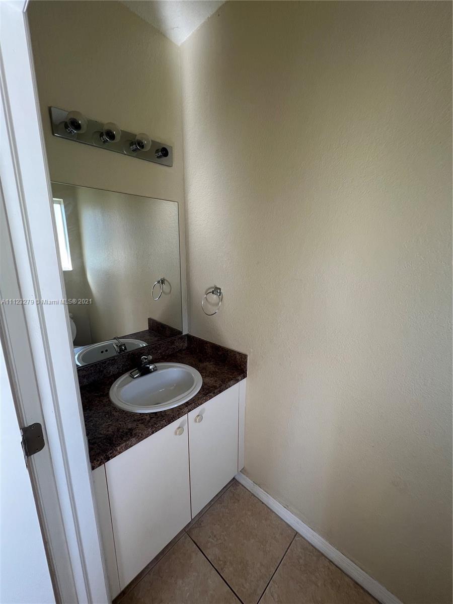 20441 Northwest 15th Avenue, Unit 8 Miami Gardens, FL 33169 - Photo 10 of 30 a bathroom with a granite countertop sink and a mirror