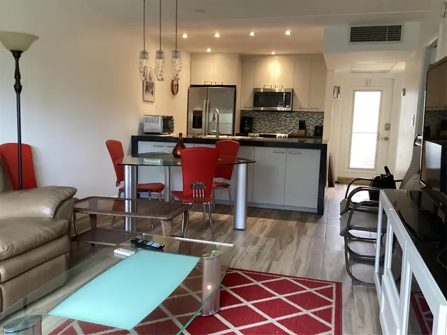 a living room with furniture a rug and kitchen view