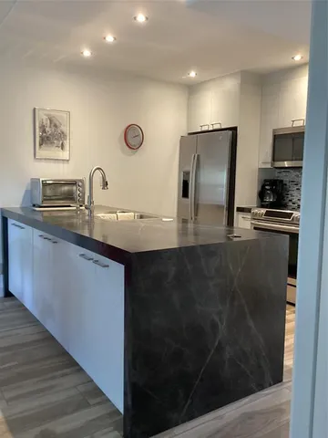 a kitchen with stainless steel appliances granite countertop a sink a stove and a refrigerator