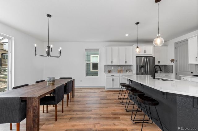 a kitchen with kitchen island a dining table chairs sink and cabinets