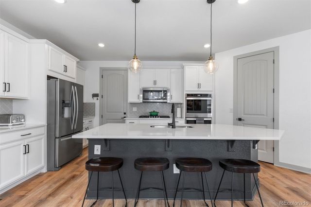 a large kitchen with granite countertop a table chairs stainless steel appliances and cabinets