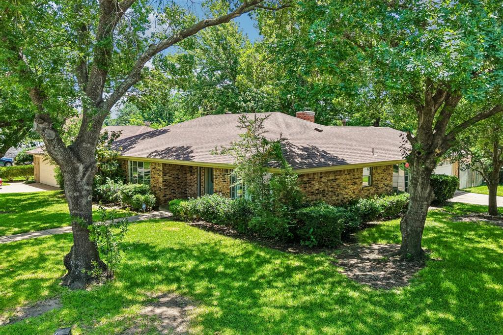 1600 South Timber Court Benbrook, TX 76126 - Photo 26 of 30 Traditional brick home featuring a pitched shingle roof, mature front yard trees, manicured shrubbery, and a concrete driveway