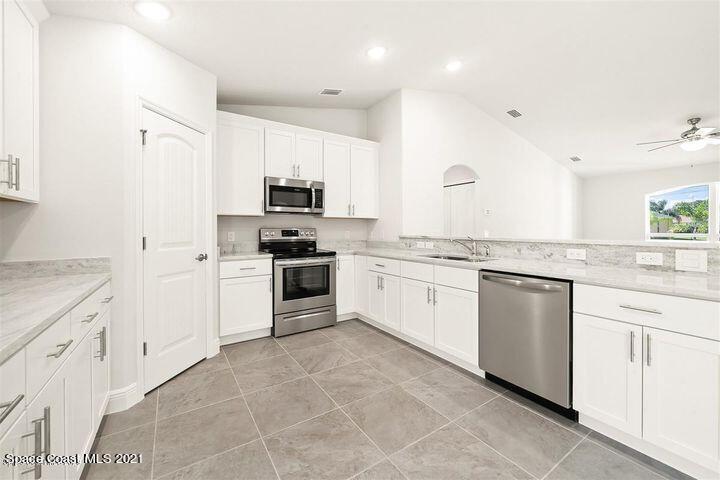 1336 Rabbit Street Southeast Palm Bay, FL 32909 - Photo 5 of 16 a kitchen with granite countertop white cabinets and white appliances