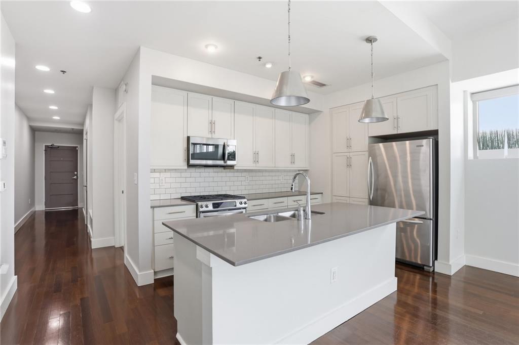 1100 Howell Mill Road Northwest, Unit 608 Atlanta, GA 30318 - Photo 7 of 37 a kitchen with stainless steel appliances granite countertop a sink a stove a refrigerator and island with wooden floor
