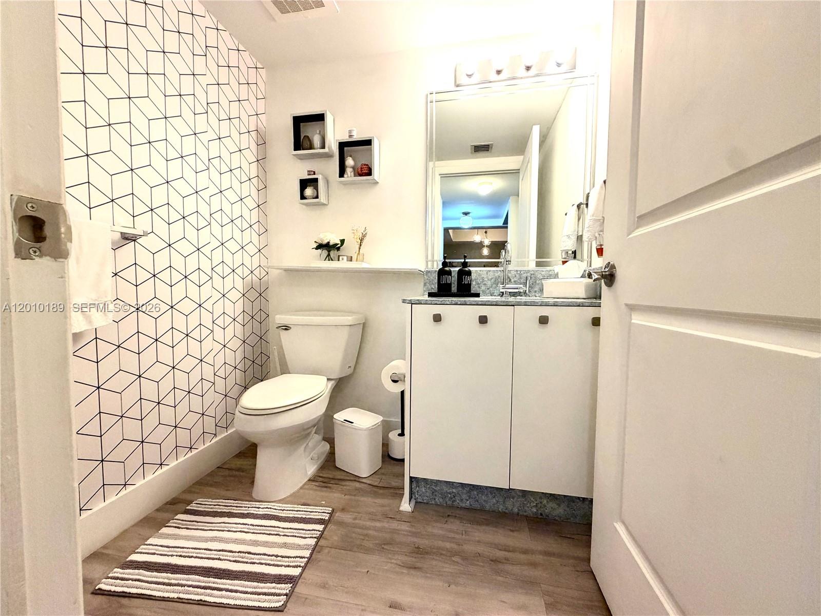 2641 North Flamingo Road, Unit TH4N Sunrise, FL 33323 - Photo 11 of 30 a bathroom with a toilet a sink and a mirror