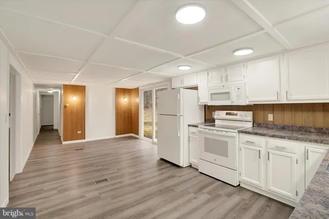 a kitchen with stainless steel appliances granite countertop a stove a sink and white cabinets with wooden floor