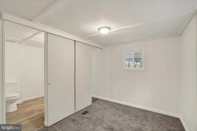 an empty room with wooden floor and bathroom view