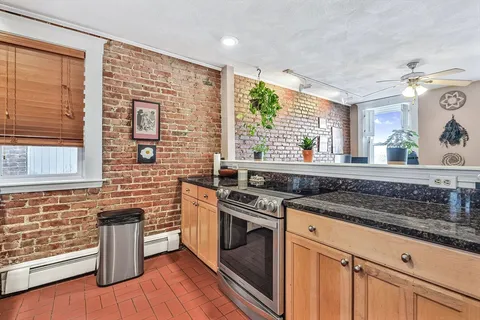 a kitchen with a stove a sink and wooden floor