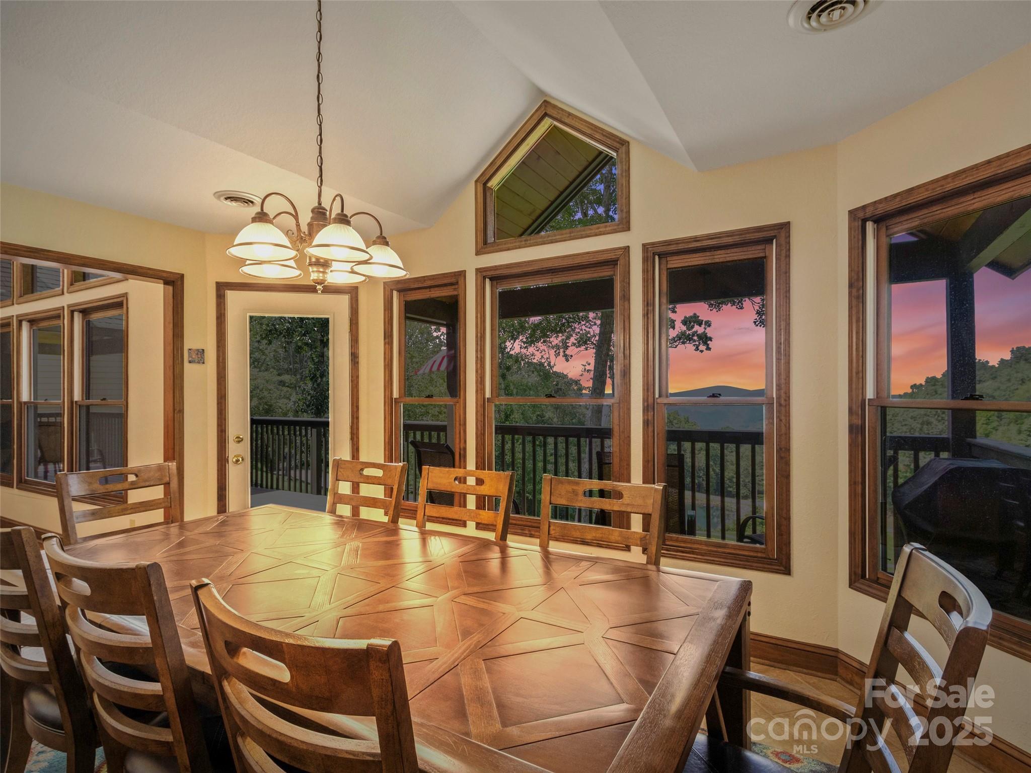 91 Brandy Run Road Burnsville, NC 28714 - Photo 16 of 48 a dining room with wooden floor a chandelier a glass table and chairs