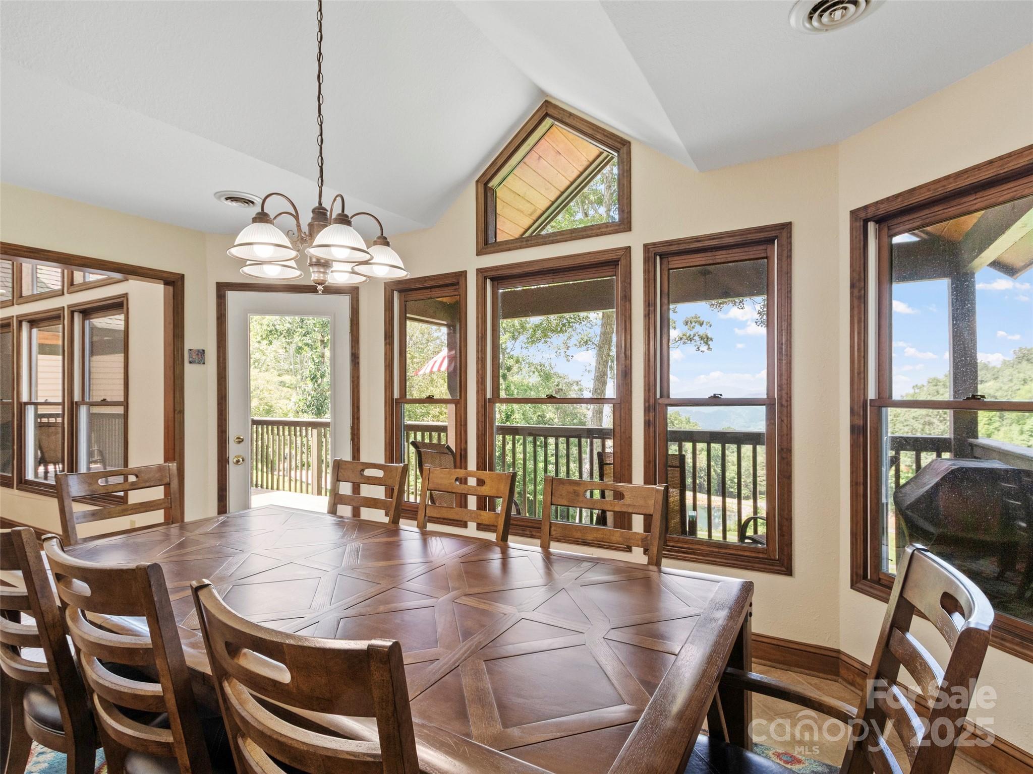 91 Brandy Run Road Burnsville, NC 28714 - Photo 9 of 48 a dining room with wooden floor a chandelier a glass table and chairs