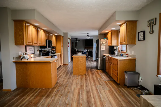 a kitchen with stainless steel appliances a sink a counter top space a large window and wooden floor