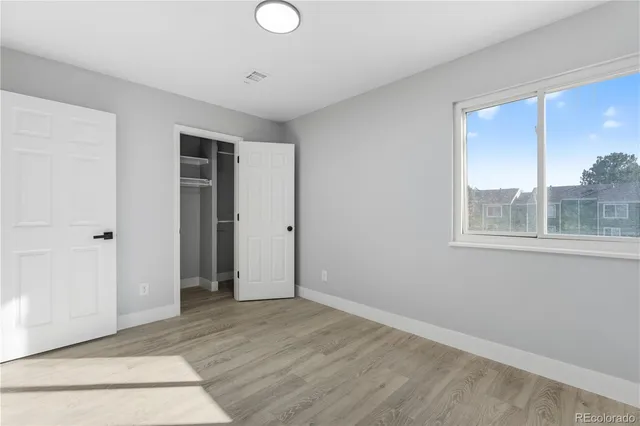 a view of an empty room with window and wooden floor