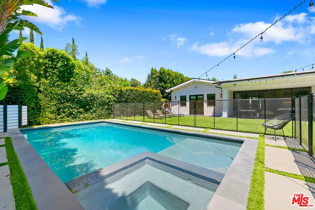 a view of swimming pool with lawn chairs under an umbrella