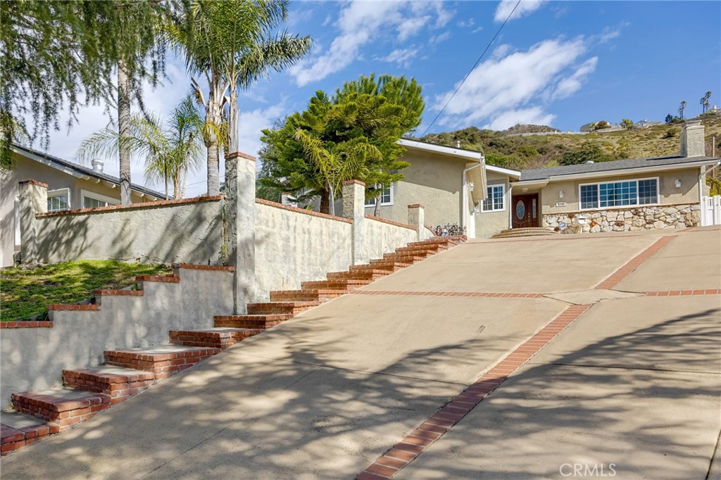 6249 Delfino Street Tujunga, CA 91042 - Photo 3 of 40 a view of a white house with a yard and potted plants