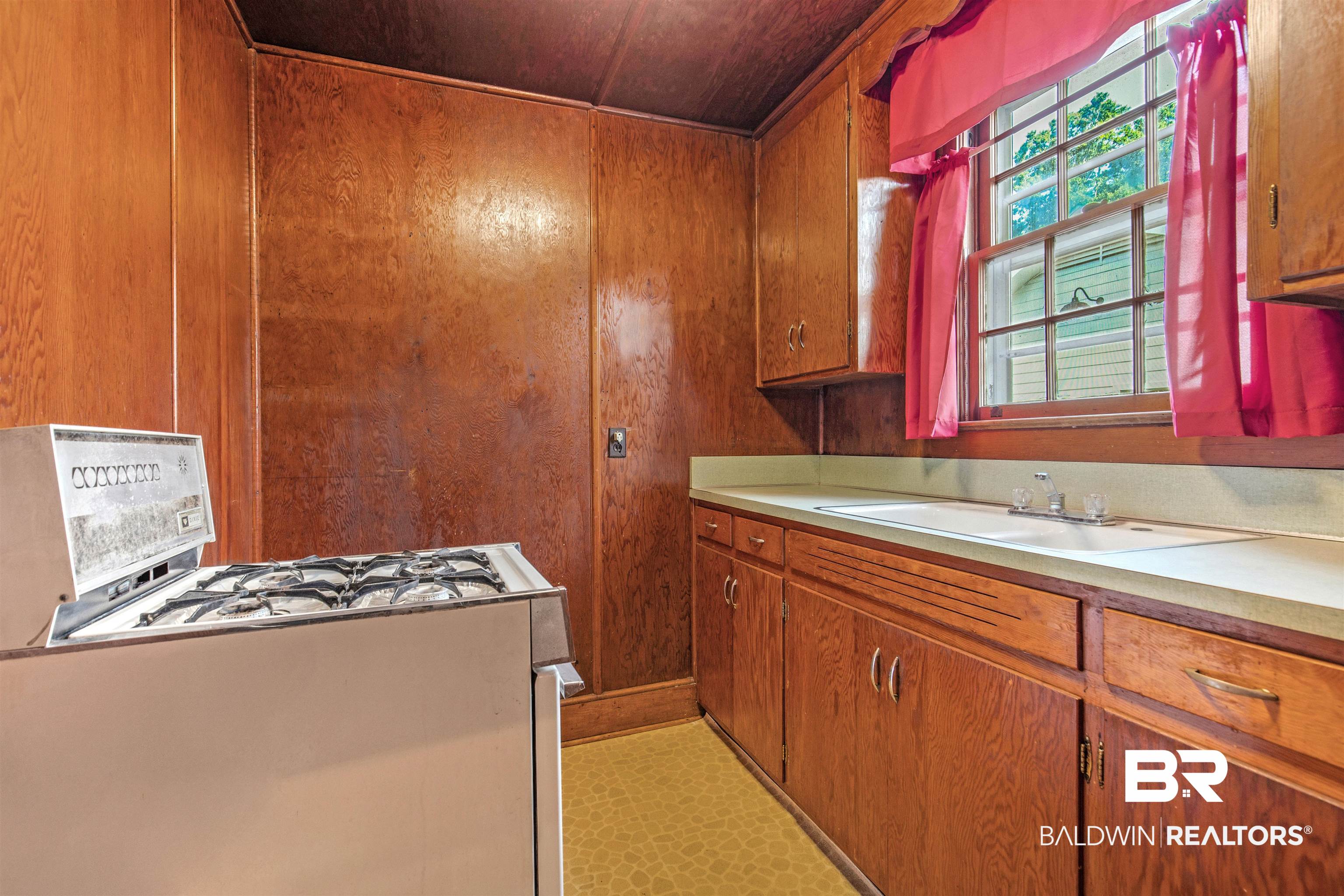 4306 Stein Street Mobile, AL 36608 - Photo 20 of 30 Kitchen featuring sink, wood walls, white range with gas cooktop, and light tile patterned floors
