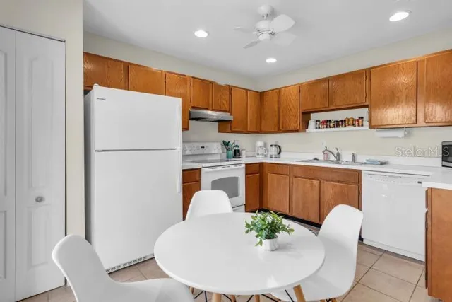 a kitchen with stainless steel appliances granite countertop a refrigerator a sink a stove a dining table and chairs