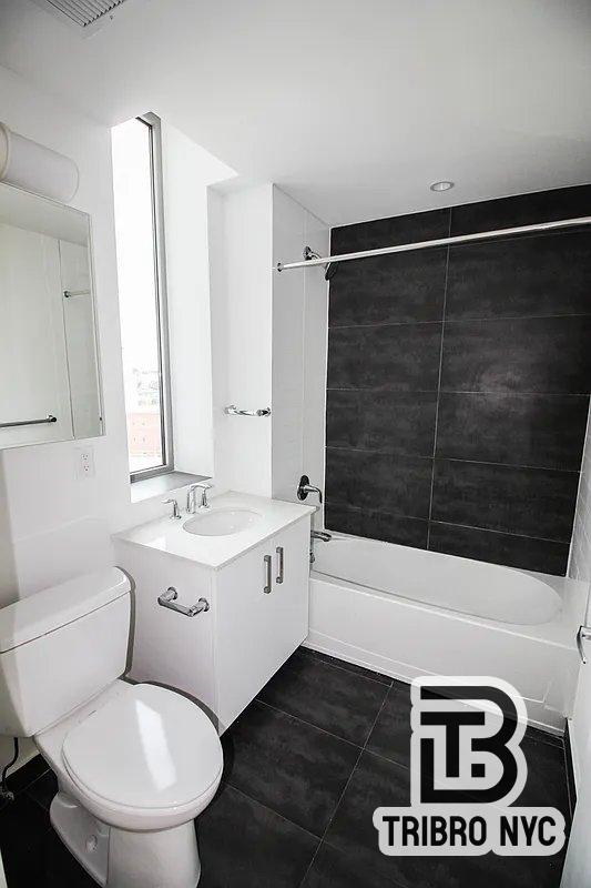 11-05 30th Road, Unit 7 Queens, NY 11102 - Photo 4 of 7 a bathroom with a toilet sink and mirror