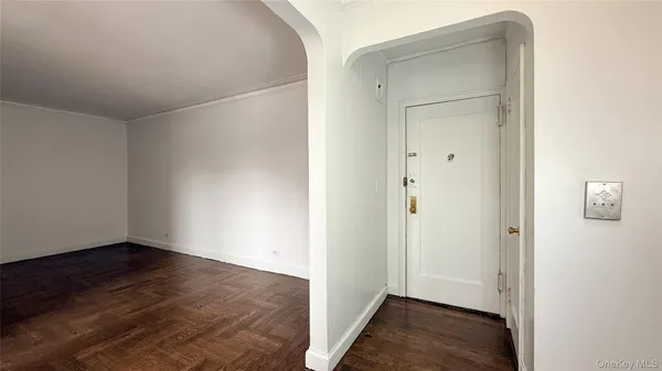 an empty room with wooden floor and a hallway