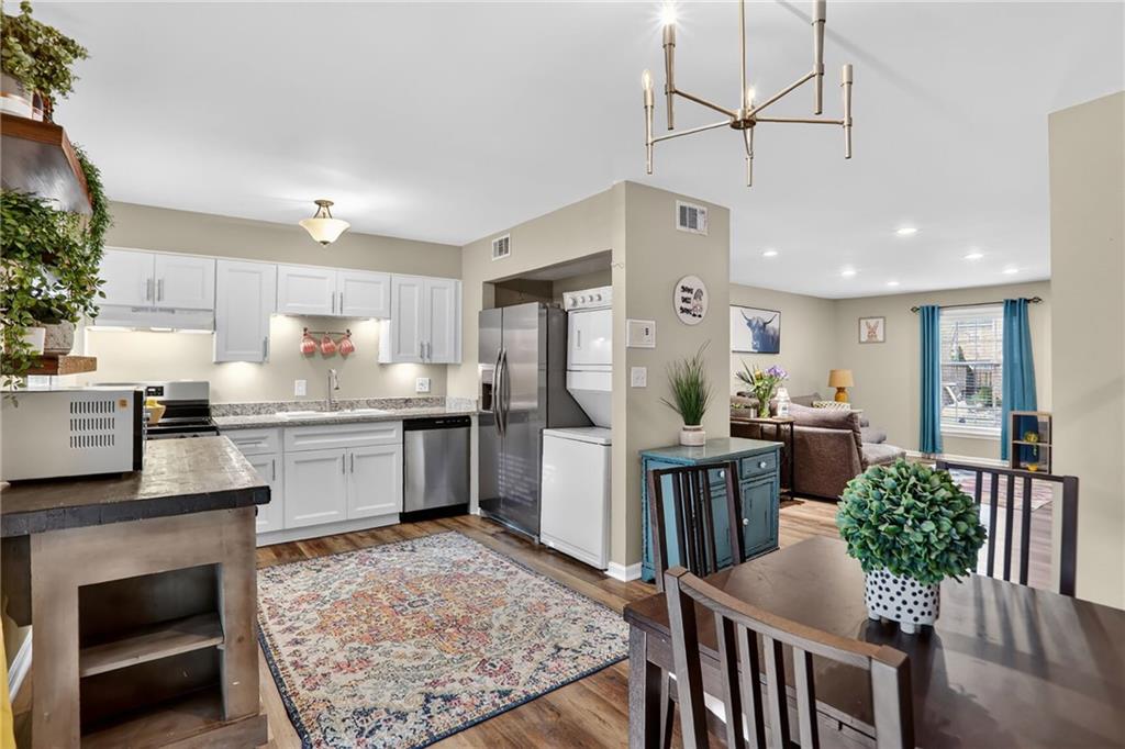 6700 Roswell Road, Unit 22B Atlanta, GA 30328 - Photo 13 of 34 a kitchen with stainless steel appliances granite countertop a refrigerator a stove and white cabinets with wooden floor
