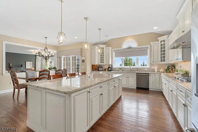 a kitchen with sink stove and white cabinets with wooden floor