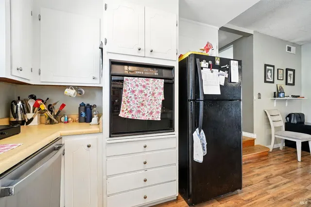 a kitchen with stainless steel appliances white cabinets and wooden floor