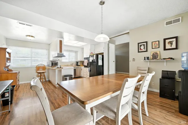 a view of a dining room and livingroom with furniture wooden floor a chandelier