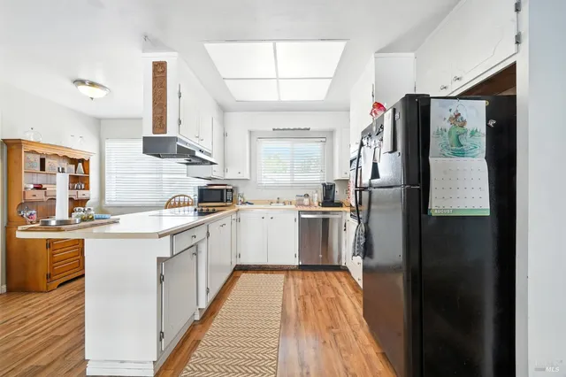 a kitchen with a refrigerator a sink and dishwasher with wooden floor