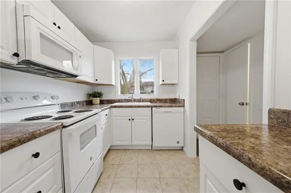 a kitchen with white cabinets appliances and a window