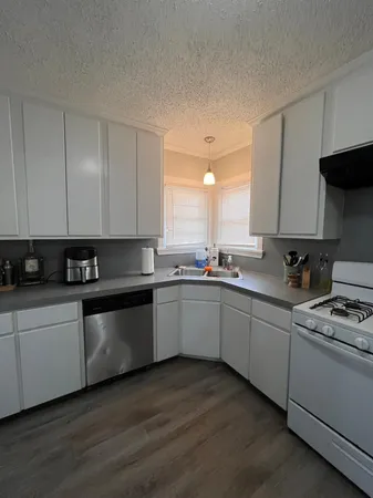 a kitchen with stainless steel appliances granite countertop a stove a sink and white cabinets