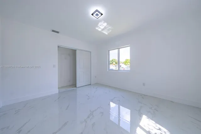 an empty room with windows and closet