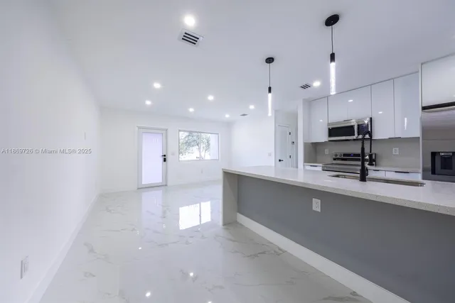 a view of kitchen with kitchen island stainless steel appliances sink and cabinets