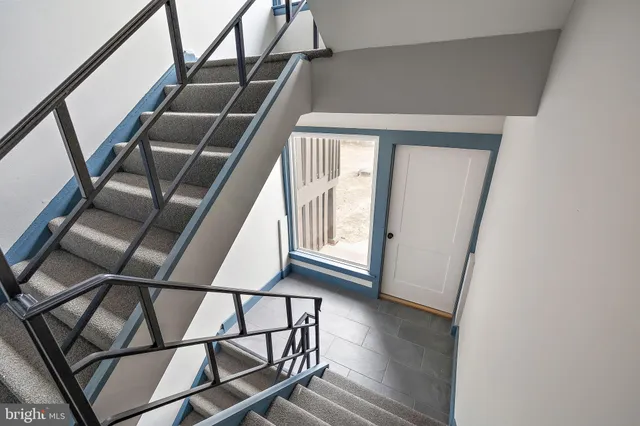 a view of staircase with railing and white walls