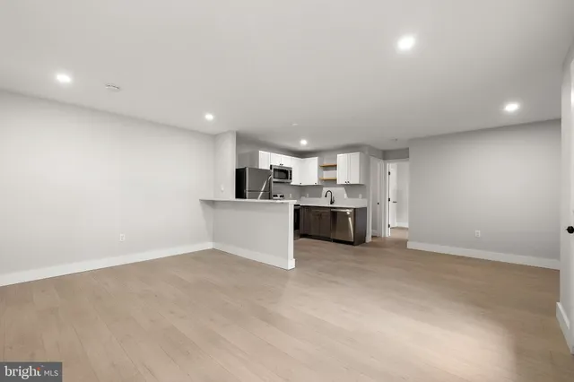 a large white kitchen with kitchen island a sink stainless steel appliances and cabinets