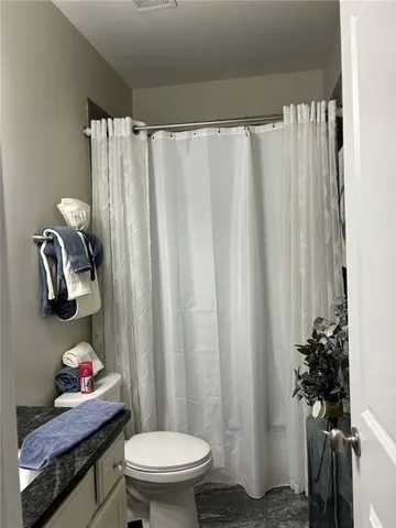 a bathroom with a toilet a sink and curtain