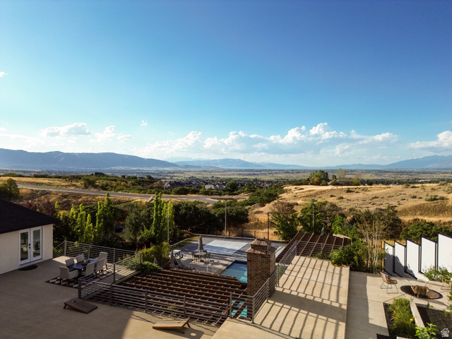 912 North Loafer Canyon Road Elk Ridge, UT 84651 - Photo 92 of 98 Expansive concrete patio with metal railing, an outdoor fire pit, and a swimming pool with cover