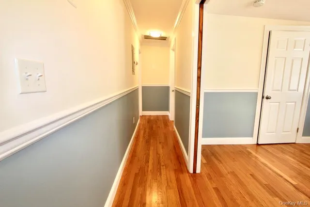 a view of a hallway with wooden floor and a bathroom